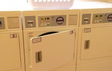 A clothesdryer with a laundry basket sitting atop it.